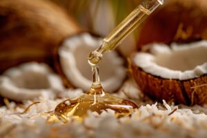 Golden oil drop drips from pipette. Background of fresh coconuts, white flakes. Concept: natural beauty products, skincare, tropical wellness retreats.